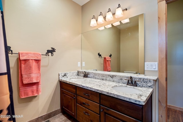 full bath featuring double vanity, toilet, baseboards, and a sink