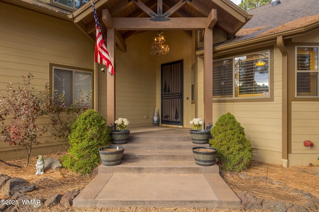 view of exterior entry featuring a porch and a shingled roof