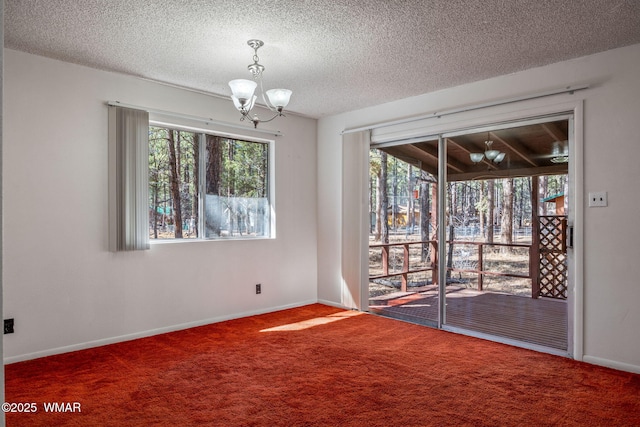 unfurnished room featuring carpet floors, a notable chandelier, a textured ceiling, and baseboards