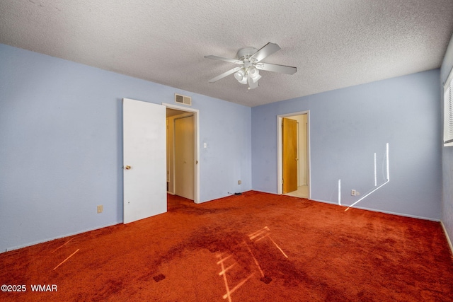 carpeted spare room with a textured ceiling, visible vents, and a ceiling fan