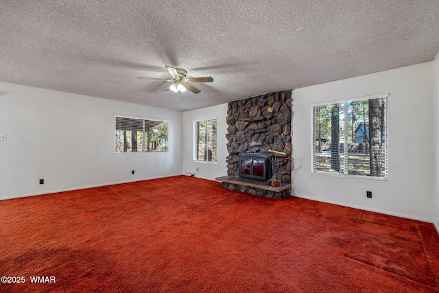 unfurnished living room with a ceiling fan, carpet, plenty of natural light, and a stone fireplace