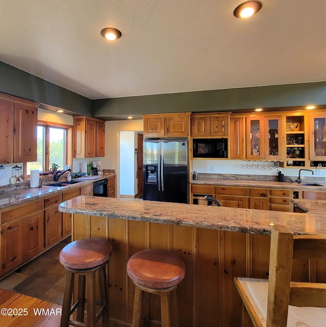 822 E 1st Ln, Eagar, AZ 85925 - kitchen featuring black appliances, a sink, a kitchen breakfast bar, and brown cabinetry