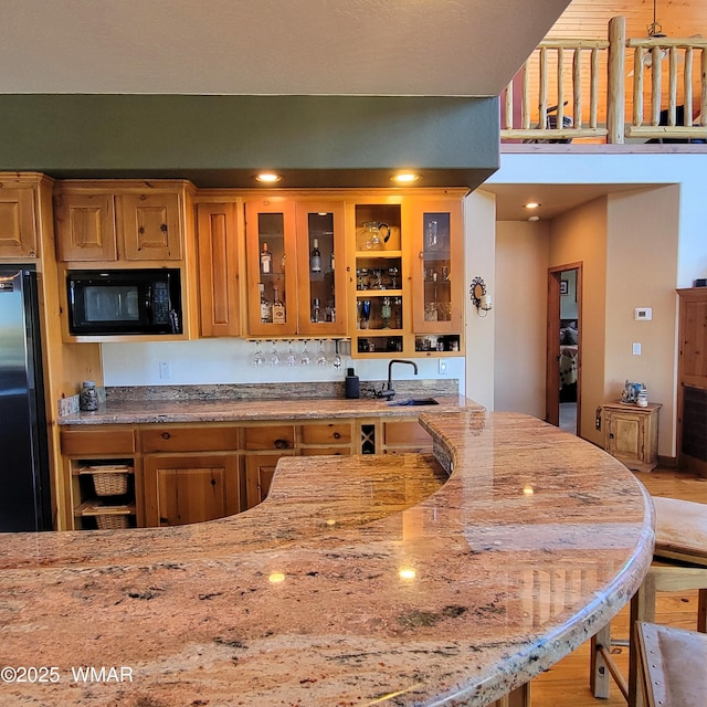 822 E 1st Ln, Eagar, AZ 85925 - kitchen with black appliances, a sink, light stone countertops, glass insert cabinets, and wood finished floors