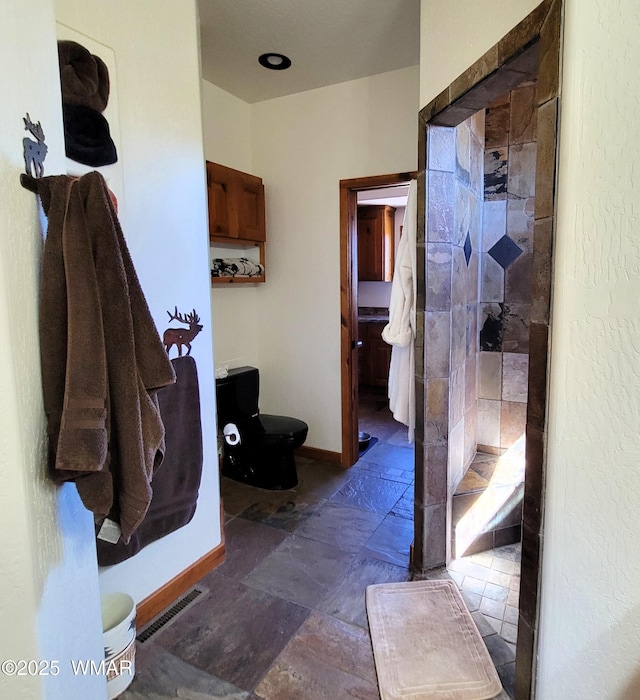 822 E 1st Ln, Eagar, AZ 85925 - bathroom featuring stone tile floors, toilet, a stall shower, and baseboards