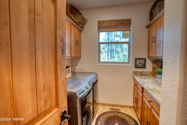 laundry area featuring visible vents, independent washer and dryer, cabinet space, and baseboards