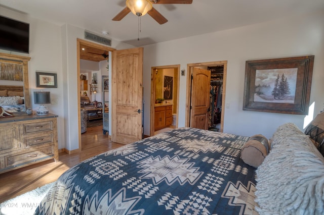 bedroom featuring visible vents, ceiling fan, light wood-style flooring, a walk in closet, and a closet