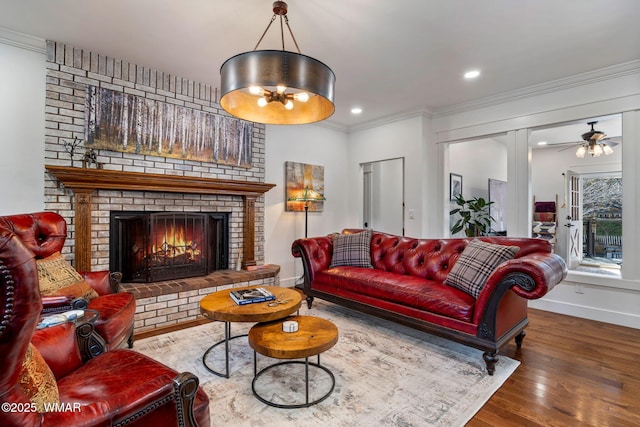 living room featuring recessed lighting, wood finished floors, baseboards, ornamental molding, and a brick fireplace