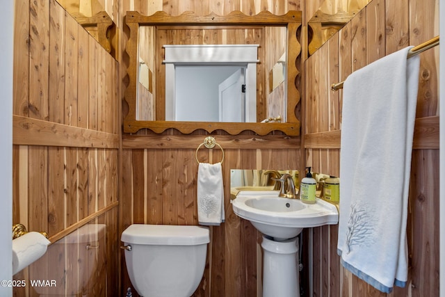 bathroom featuring wooden walls and toilet