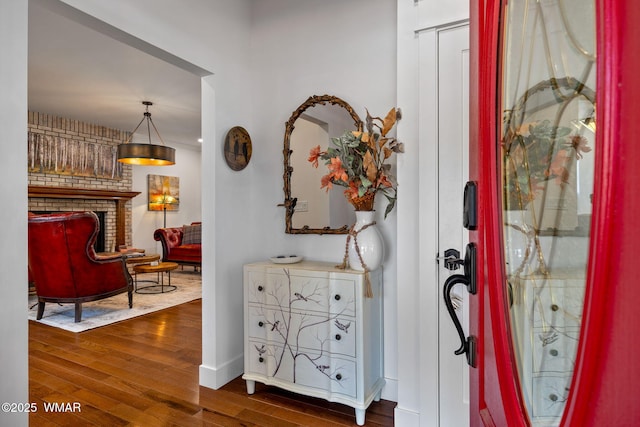 entryway featuring a brick fireplace, dark wood finished floors, and baseboards