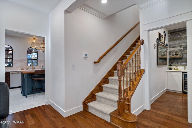 stairs featuring wine cooler, recessed lighting, wood finished floors, baseboards, and a bar