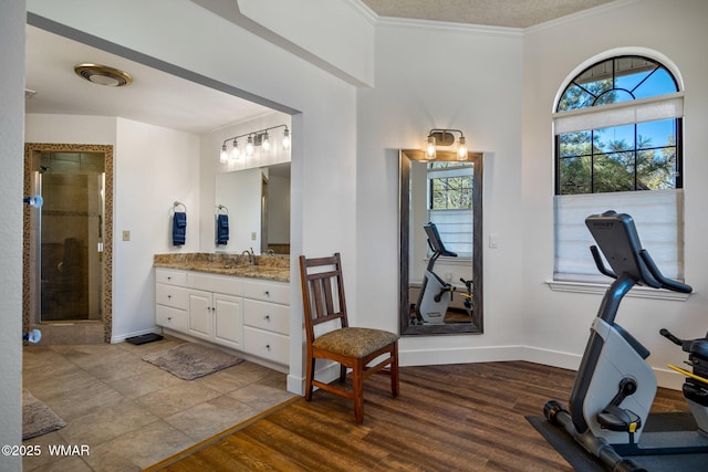 bathroom with a stall shower, crown molding, baseboards, and wood finished floors