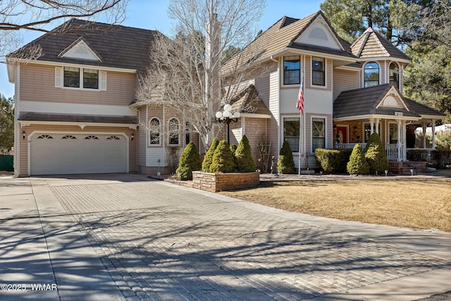 view of front facade with a porch, decorative driveway, and an attached garage