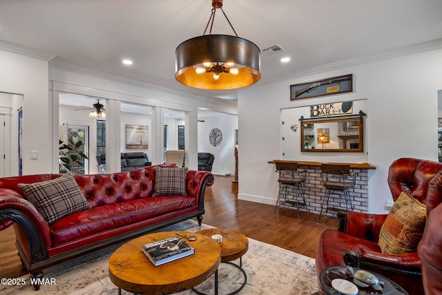 living room featuring baseboards, visible vents, wood finished floors, crown molding, and recessed lighting