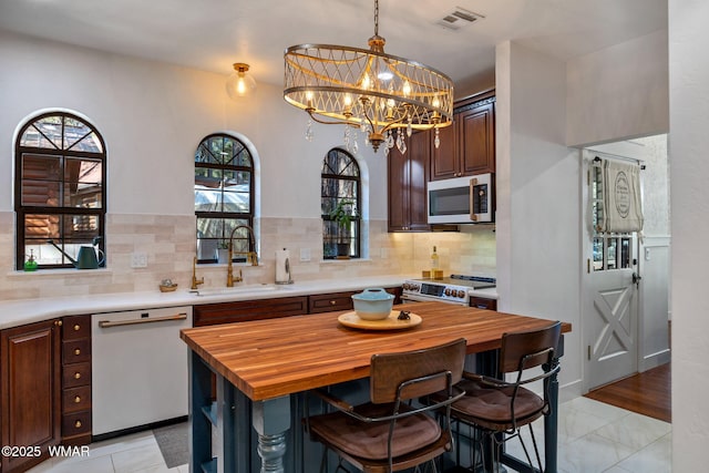 kitchen with white appliances, visible vents, wood counters, a breakfast bar area, and a sink