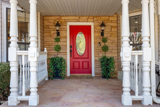 doorway to property with a porch and brick siding