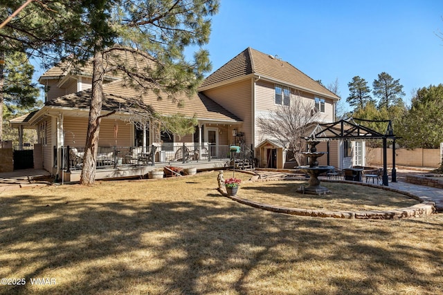 rear view of property featuring a lawn, a patio area, and a wooden deck