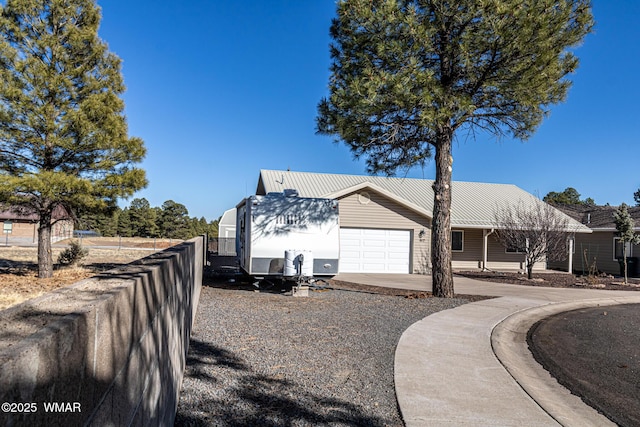 view of side of home featuring metal roof, driveway, fence, and a garage