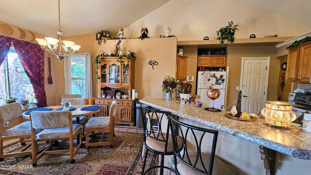 860 N Kiaya Ln, Show Low, AZ 85901 - kitchen featuring freestanding refrigerator, lofted ceiling, a chandelier, light countertops, and a breakfast bar