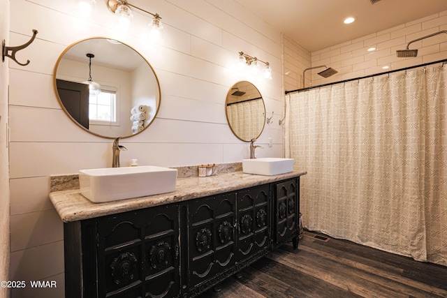 bathroom with double vanity, wood finished floors, a sink, and curtained shower