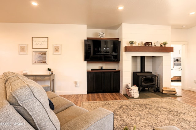 living area featuring recessed lighting, a wood stove, baseboards, and wood finished floors