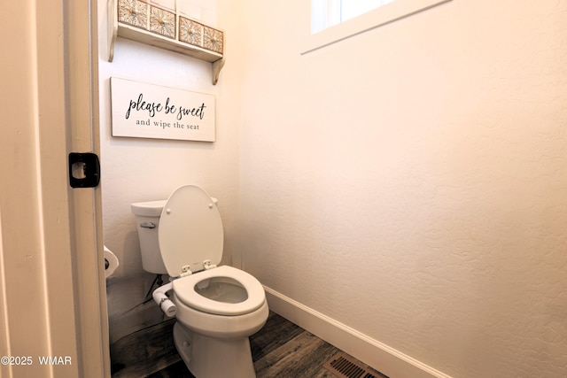 bathroom with visible vents, a textured wall, toilet, wood finished floors, and baseboards