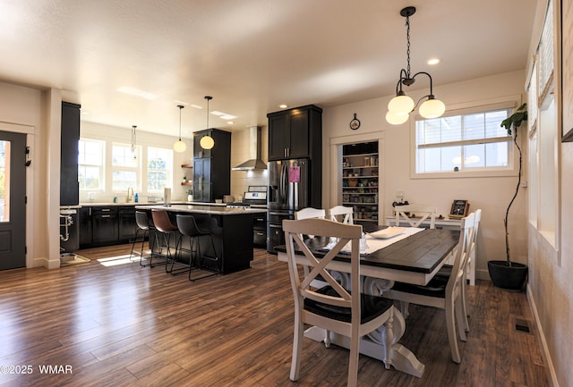 dining space with dark wood-type flooring, a healthy amount of sunlight, and baseboards