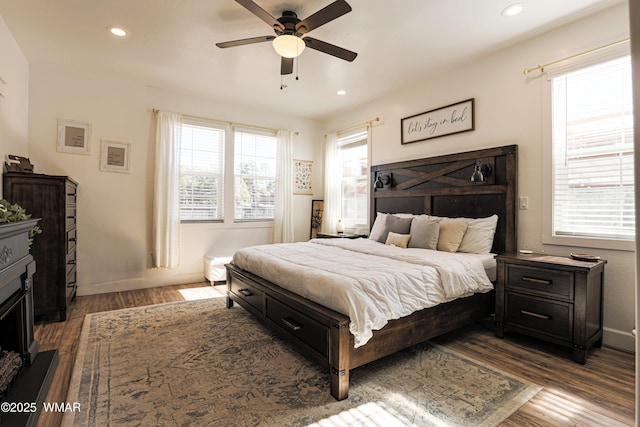 bedroom with a fireplace, dark wood finished floors, recessed lighting, ceiling fan, and baseboards