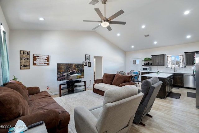 living room featuring vaulted ceiling, recessed lighting, light wood-style flooring, a ceiling fan, and visible vents