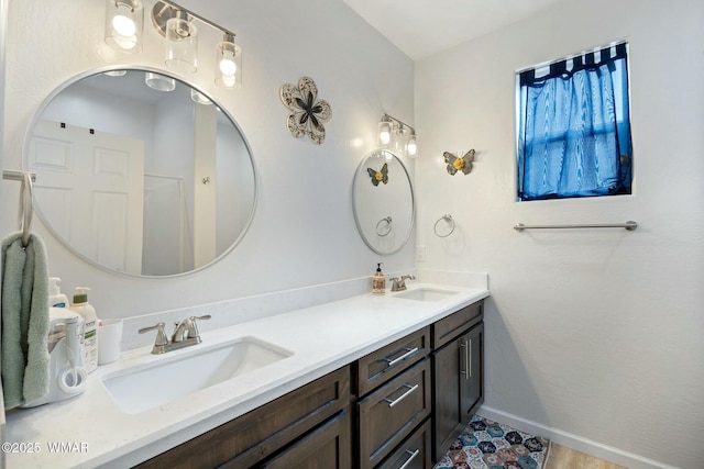 bathroom with double vanity, a sink, and baseboards