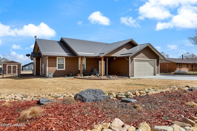 view of front of house with concrete driveway, metal roof, fence, and an attached garage
