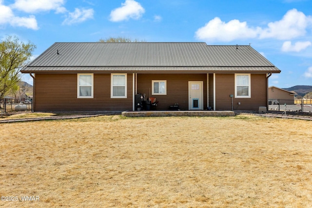 rear view of house featuring metal roof and fence