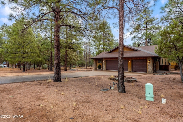 view of front of home featuring stone siding, driveway, and an attached garage