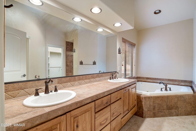 bathroom with double vanity, a garden tub, a sink, and tile patterned floors