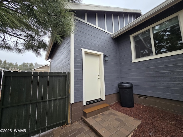 view of exterior entry with crawl space and fence