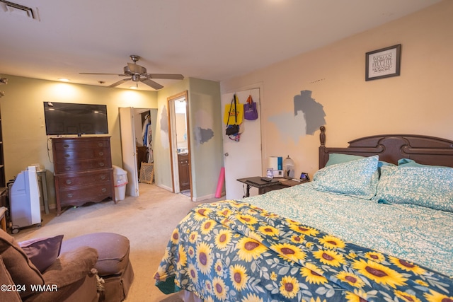 bedroom with a ceiling fan, light colored carpet, visible vents, and ensuite bathroom