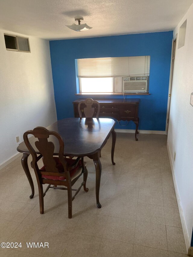 dining area with cooling unit, baseboards, visible vents, and a textured ceiling