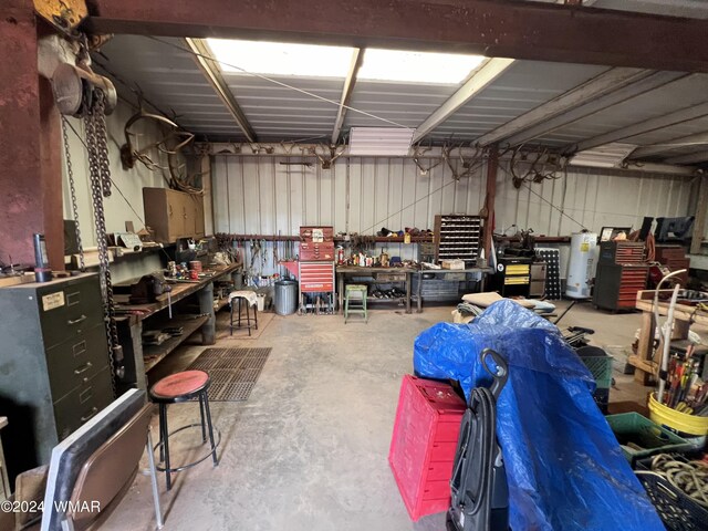 garage featuring water heater, metal wall, and a workshop area