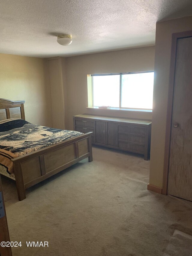 bedroom featuring light carpet and a textured ceiling