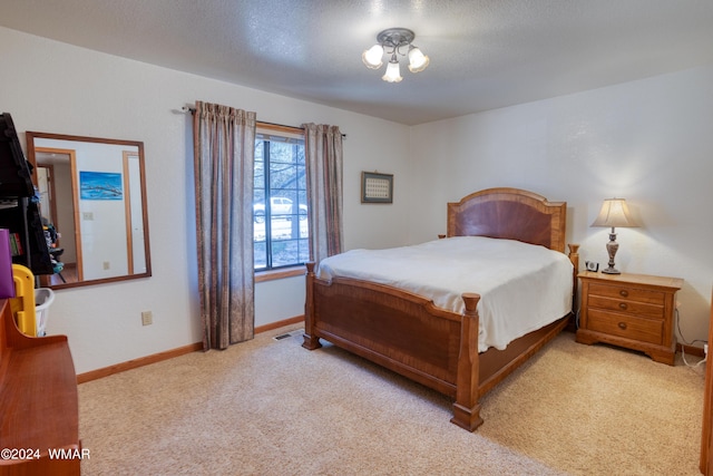 bedroom with baseboards, a textured ceiling, visible vents, and light colored carpet