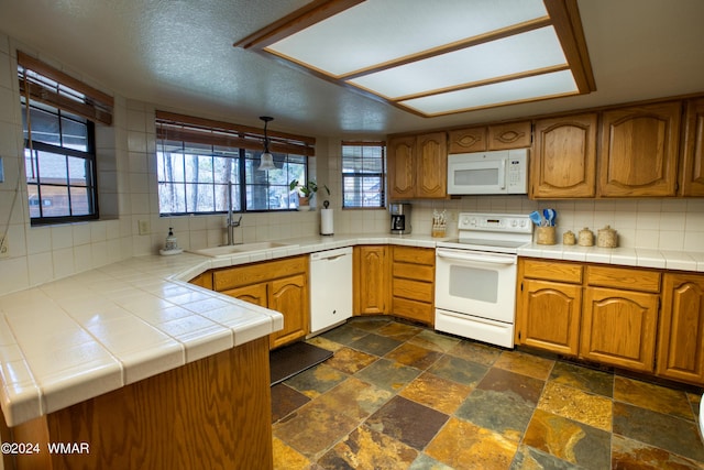 kitchen with tile counters, white appliances, a sink, and tasteful backsplash