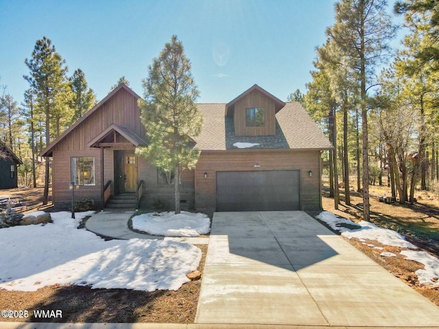 chalet / cabin featuring a garage, driveway, and a shingled roof