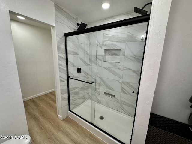 bathroom featuring a stall shower, baseboards, and wood finished floors