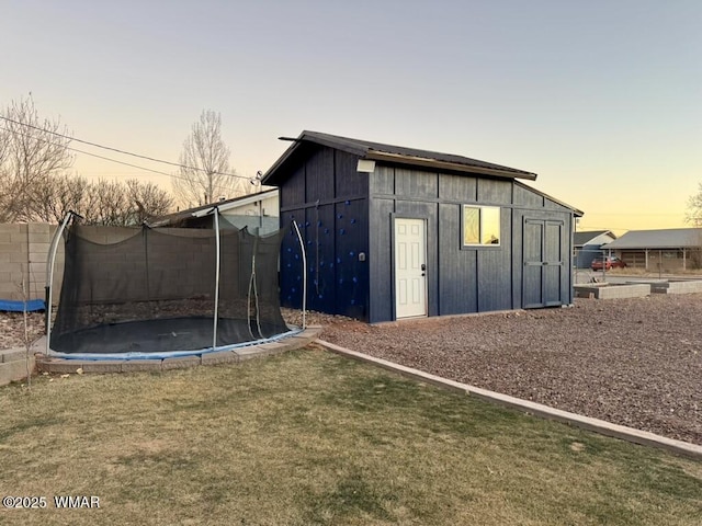 view of outdoor structure featuring a trampoline, fence, and an outdoor structure