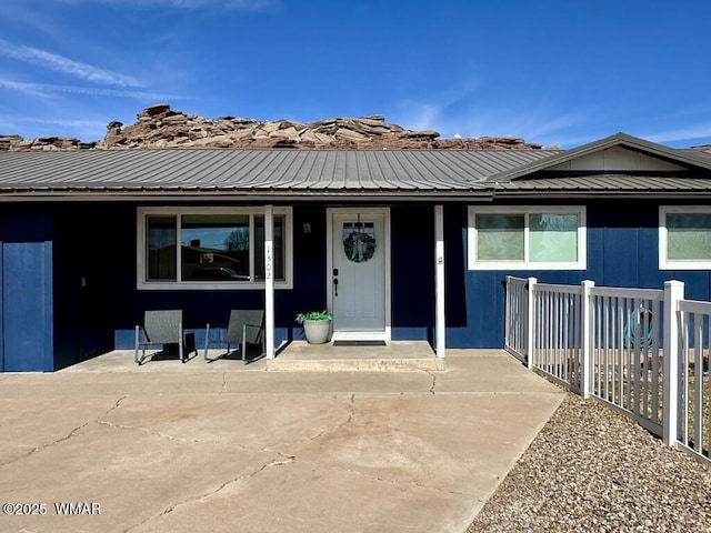 view of front facade featuring metal roof and fence