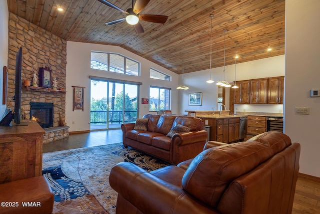 living area with wood finished floors, high vaulted ceiling, a stone fireplace, wine cooler, and wooden ceiling