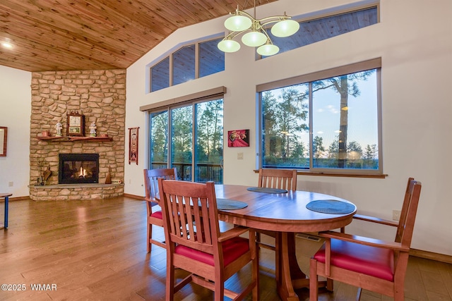 dining area with baseboards, wood ceiling, wood finished floors, and a fireplace