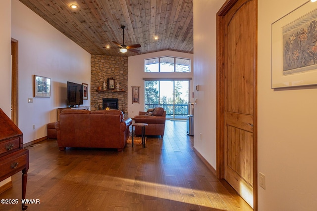 living area with wood finished floors, baseboards, ceiling fan, a stone fireplace, and wood ceiling