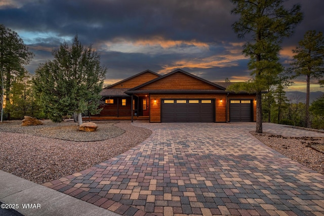 rustic home with an attached garage and decorative driveway