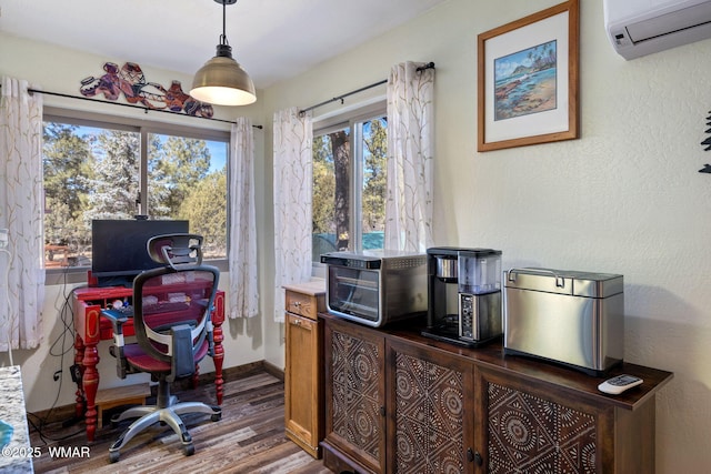 office space featuring a wall unit AC, baseboards, wood finished floors, and a textured wall