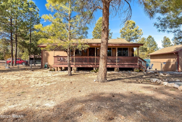 rear view of house featuring a deck and fence